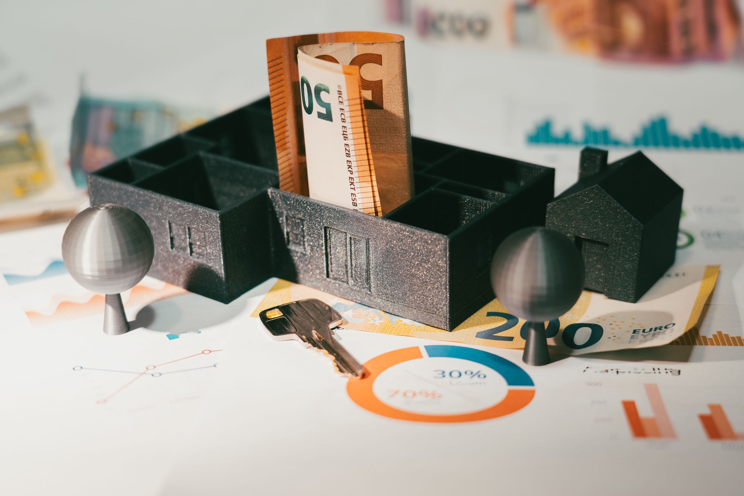 Billets euros, maquette maison et graphiques financiers