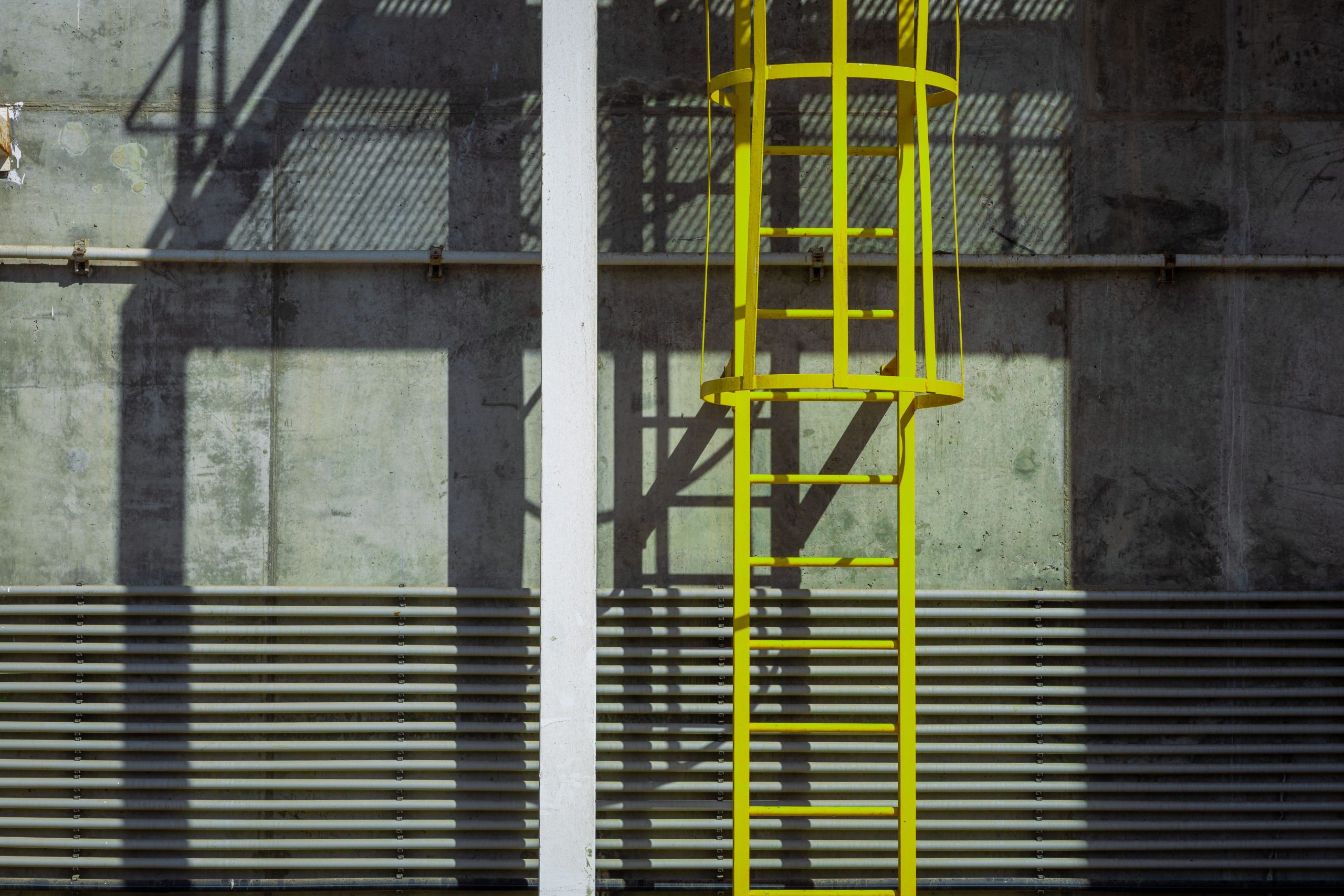 Échelle jaune façade béton industriel ombre