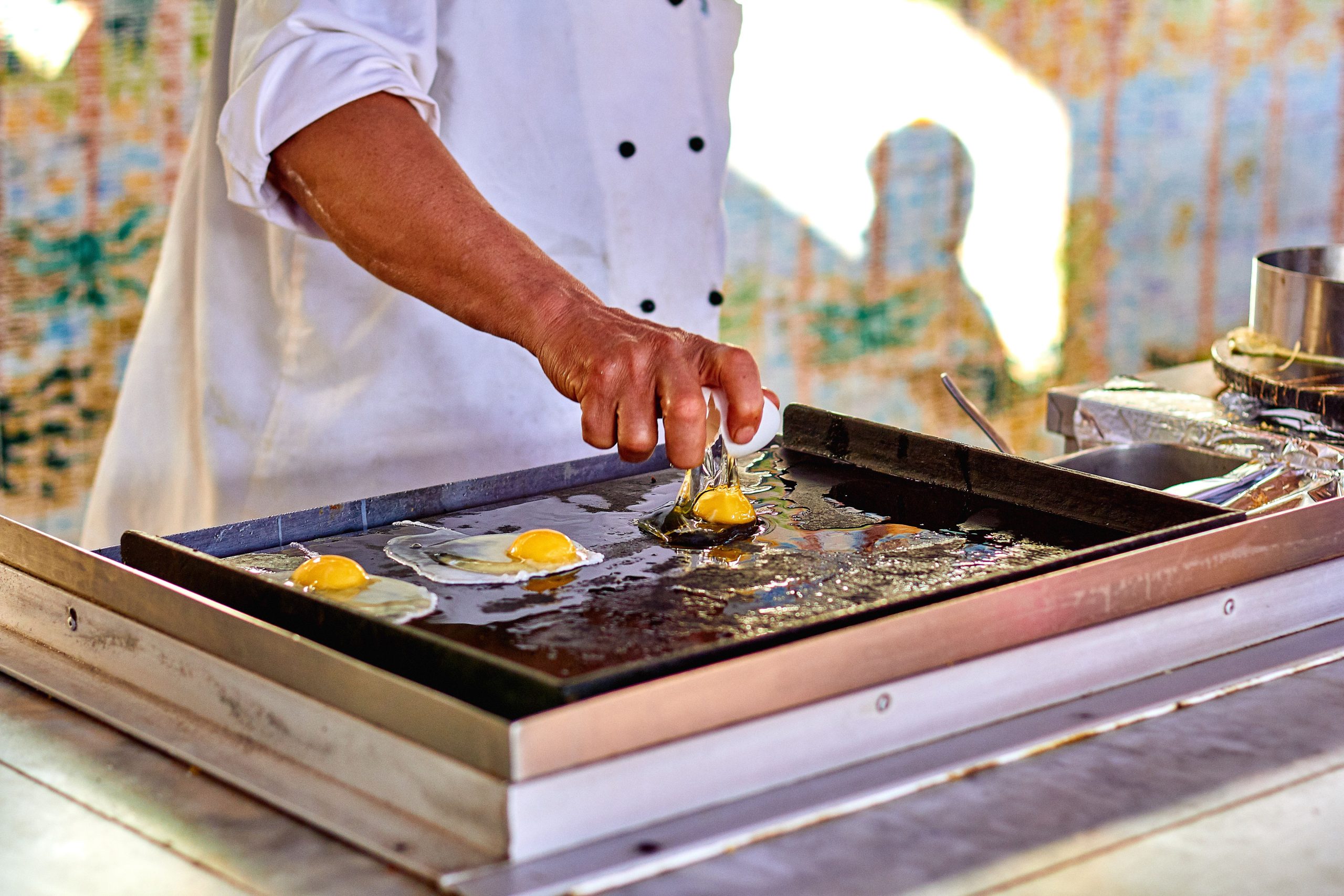 Chef cuisant oeufs frits sur plancha outdoor