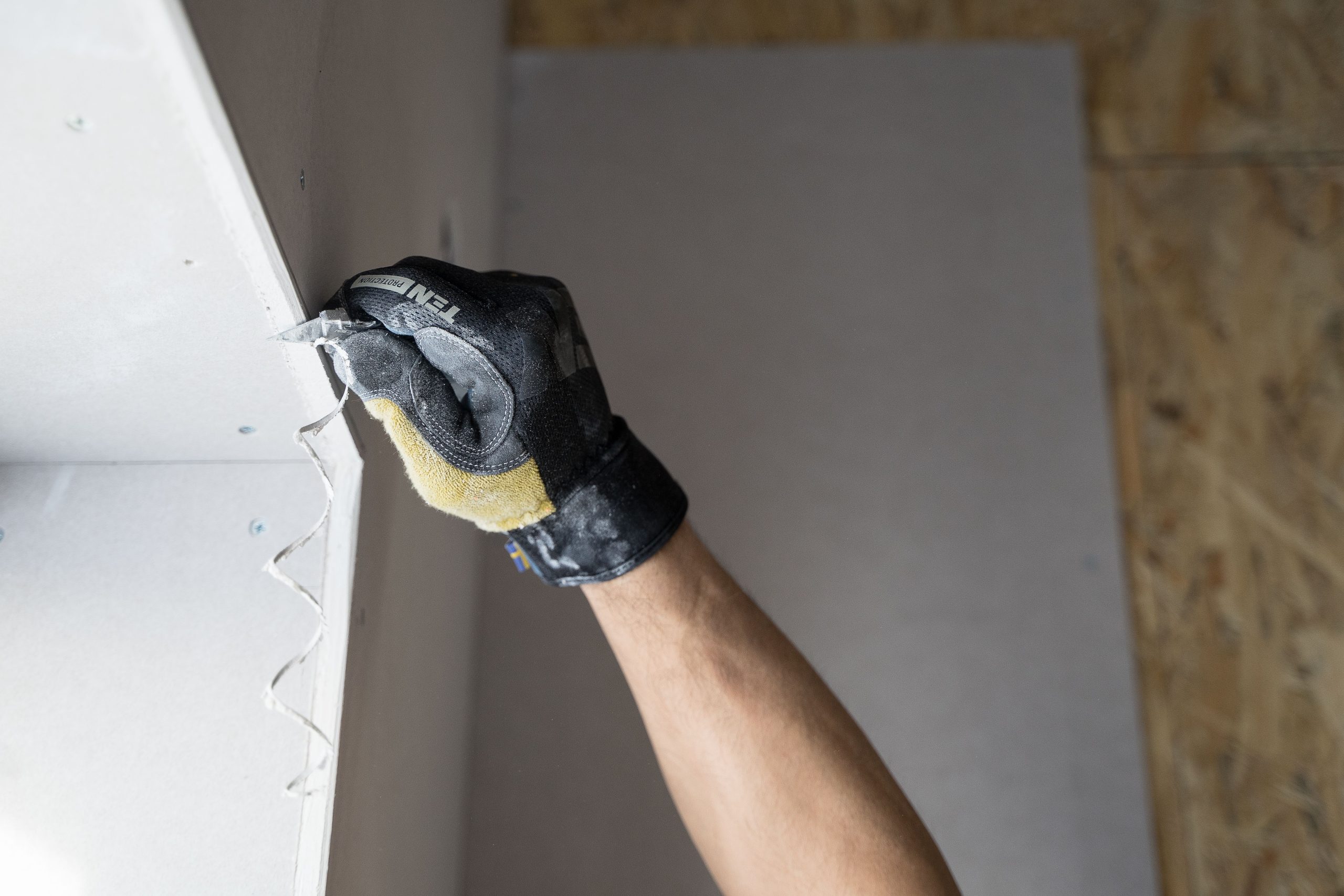 Main gantée appliquant plâtre sur mur