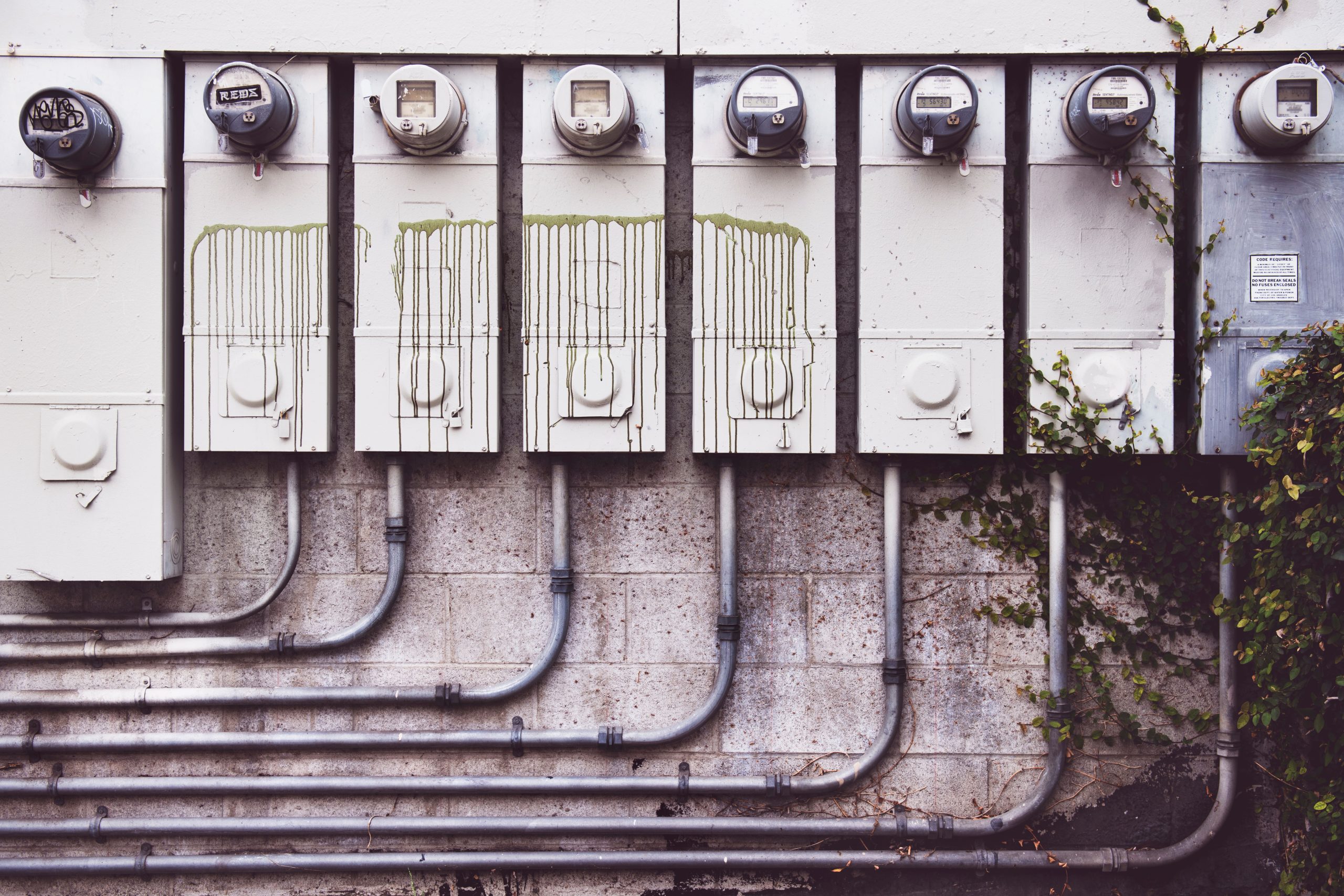 Rangée compteurs électriques extérieurs mur brique lierre