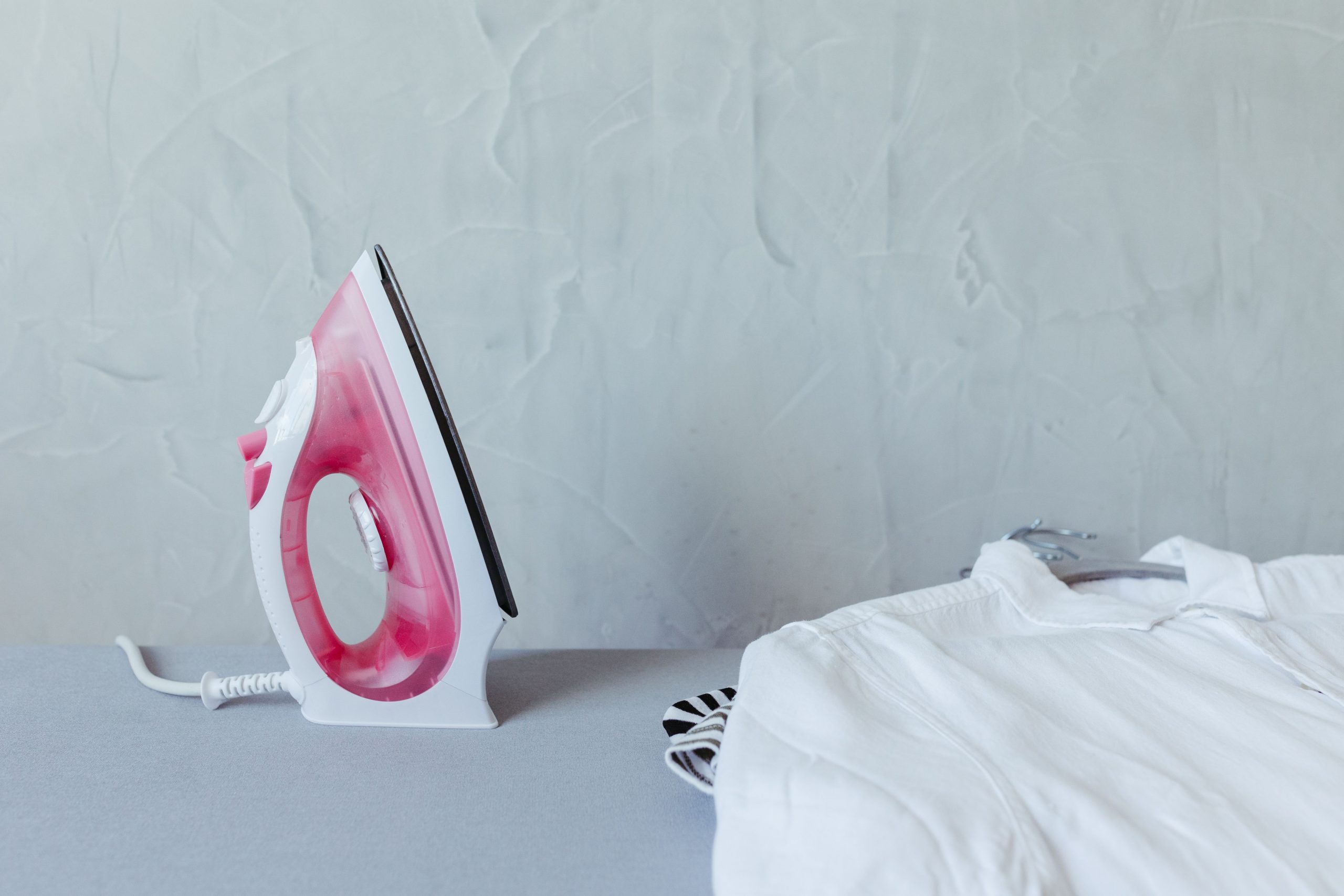Fer rose et chemise blanche sur planche à repasser