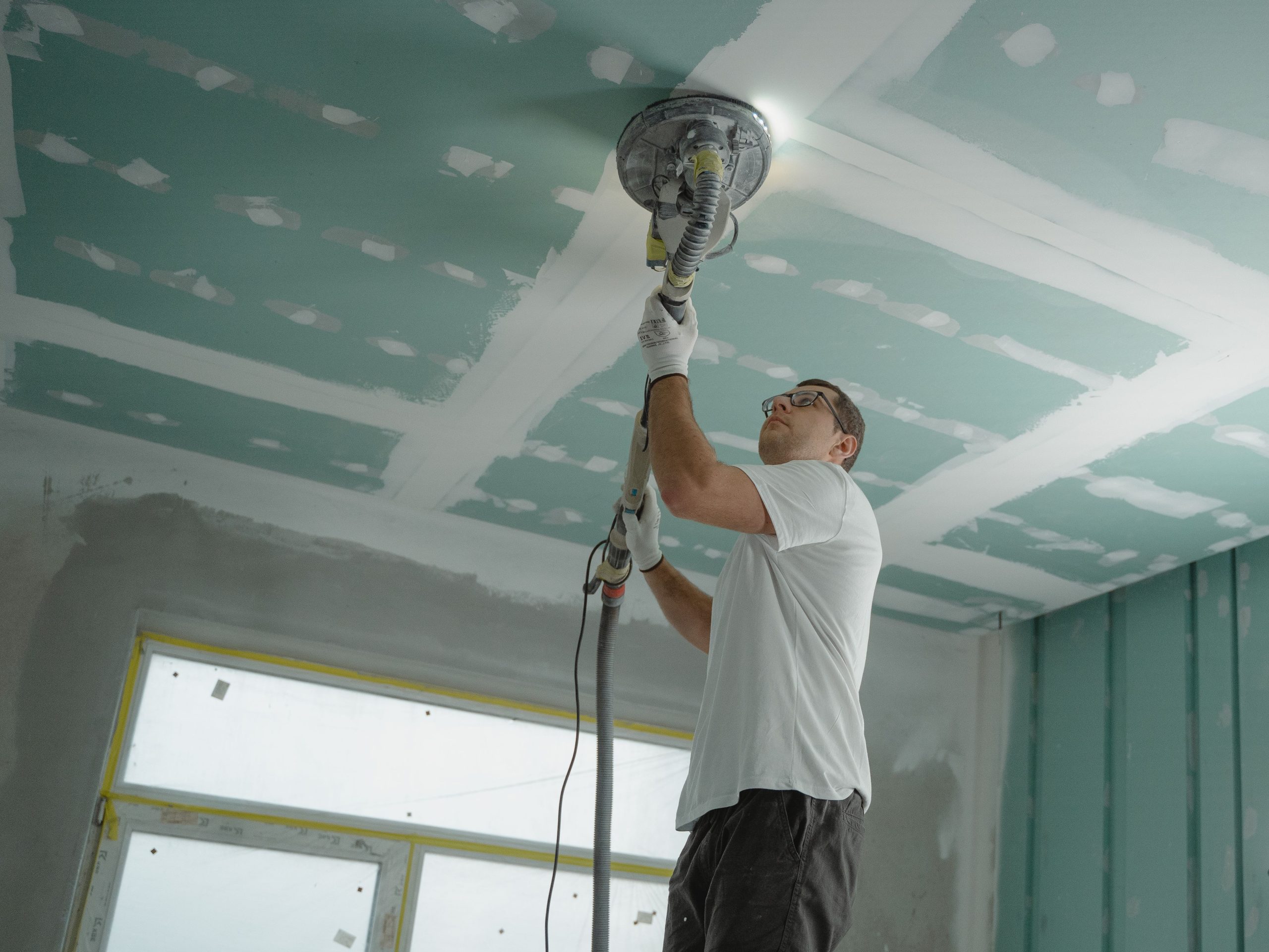 Professionnel poncant le plafond en rénovation
