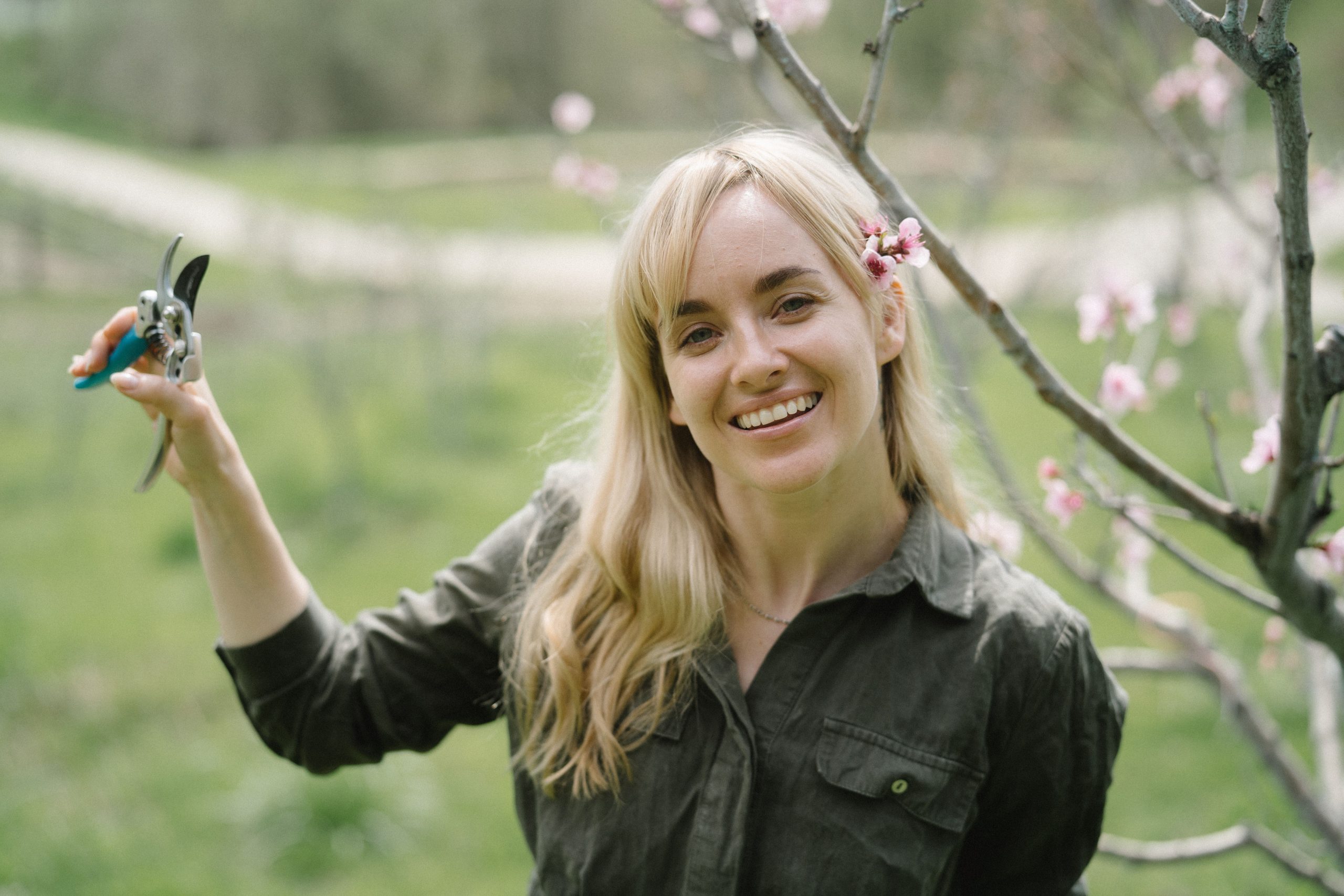 Femme souriante tenant des sécateurs sous branche fleurie
