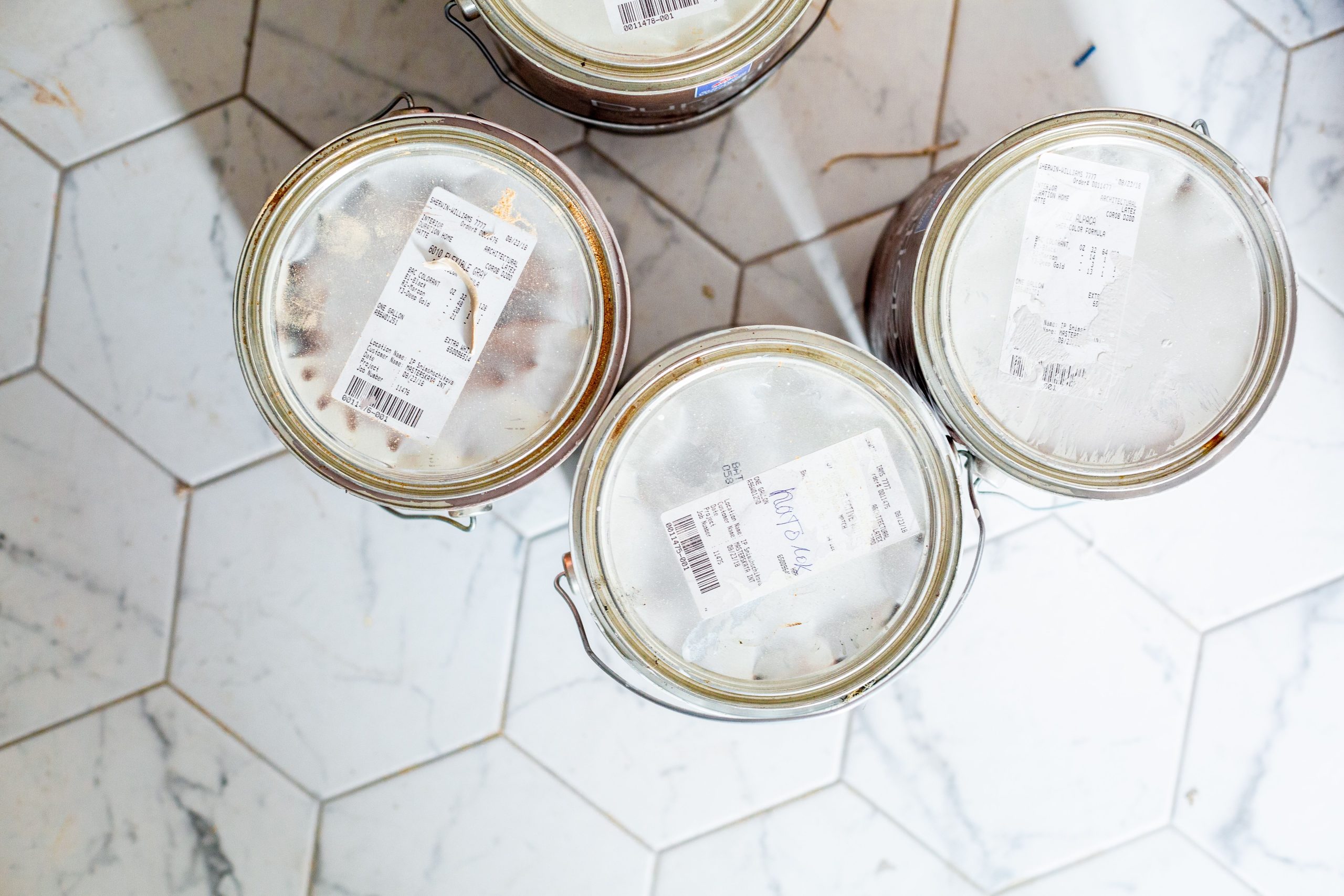 Trois pots de peinture sur carrelage hexagonal pour rénovation.